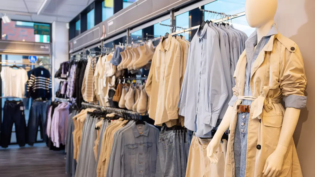 Prezentace zboží v kompletních outfitech na zadní stěně prodejny KiK
